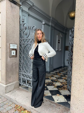 a lady wears a white cardigan with black wide leg pants